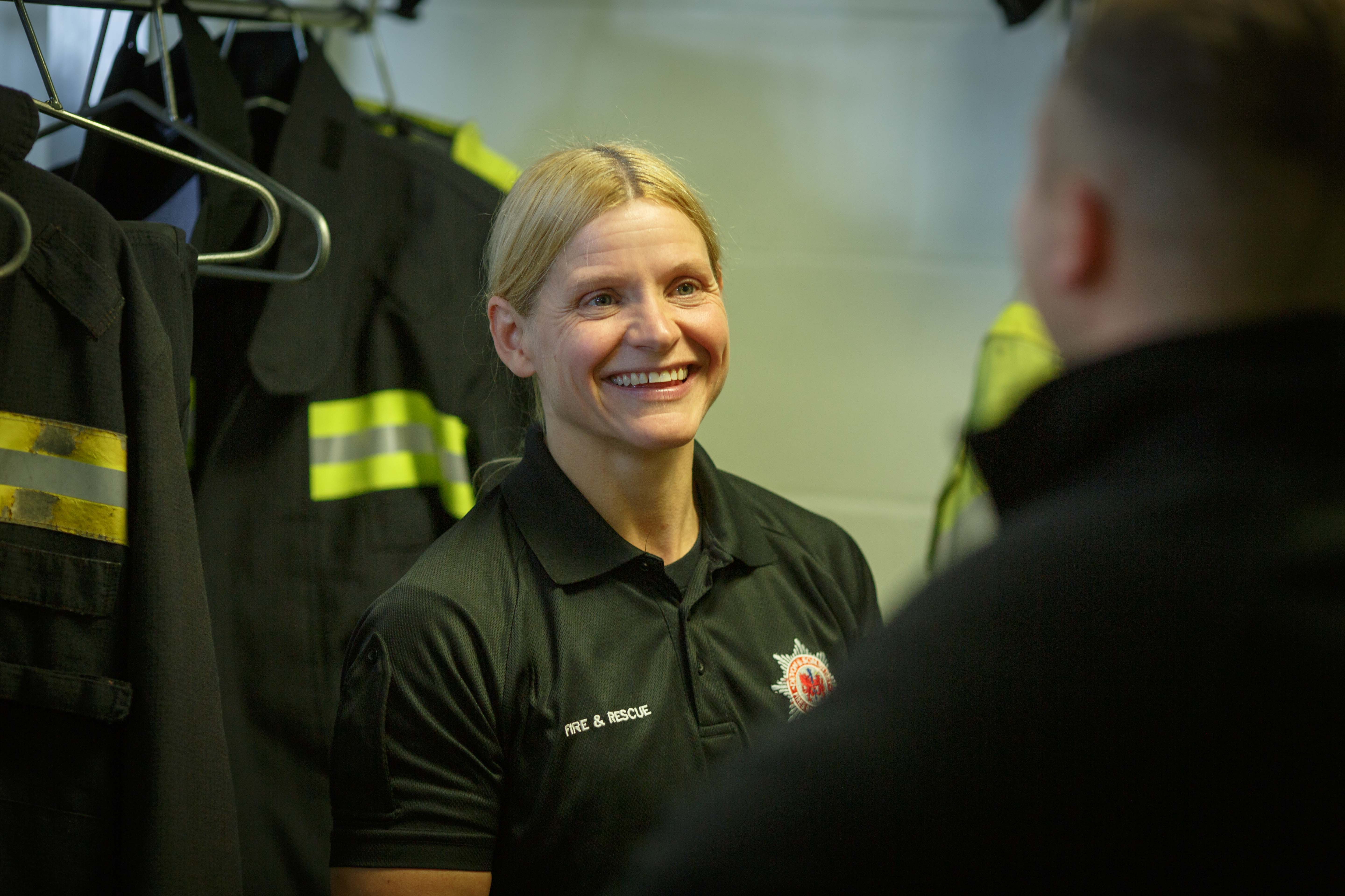 Female firefighter talking to a male firefighter in the kit room