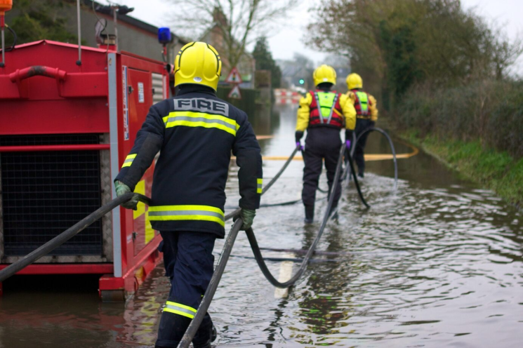 Three firefighters walking through flood water  
