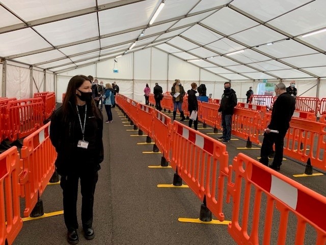 Volunteers from our Service wearing masks in a socially distanced queue to test processes at a new vaccination centre.