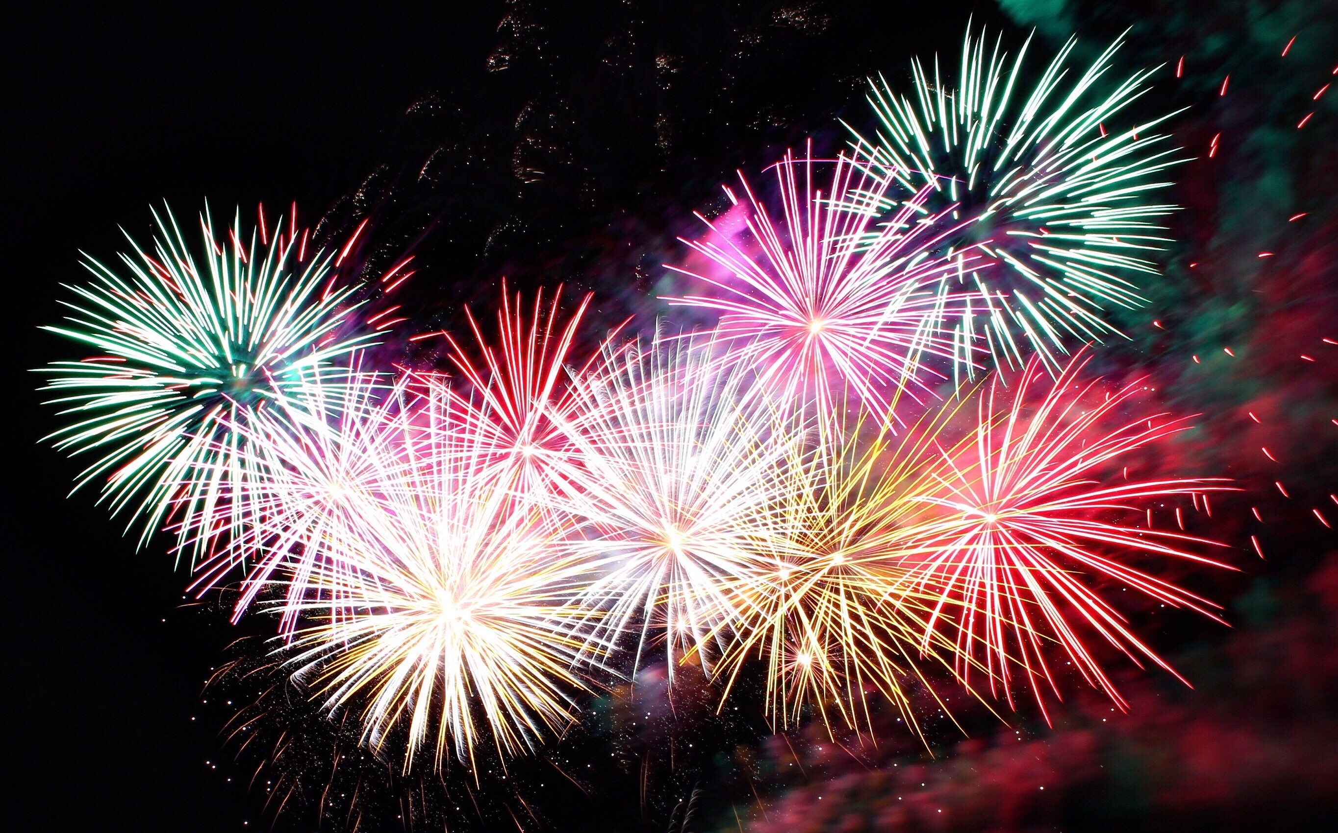 Colourful fireworks bursting in a circular pattern in a night sky.