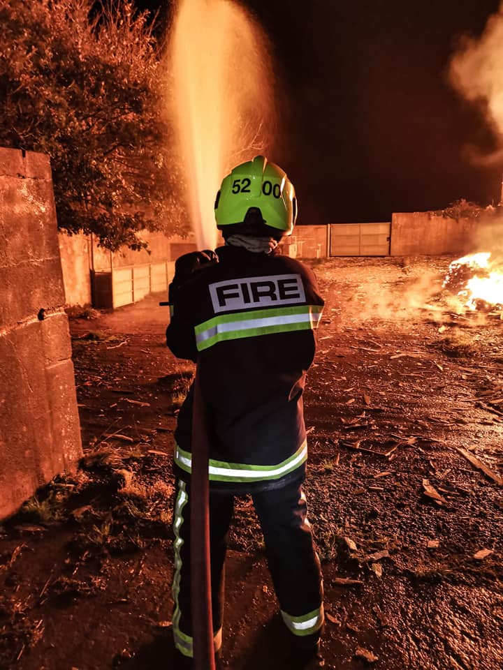 Firefighter spraying a hose and jet of water at a barn fire