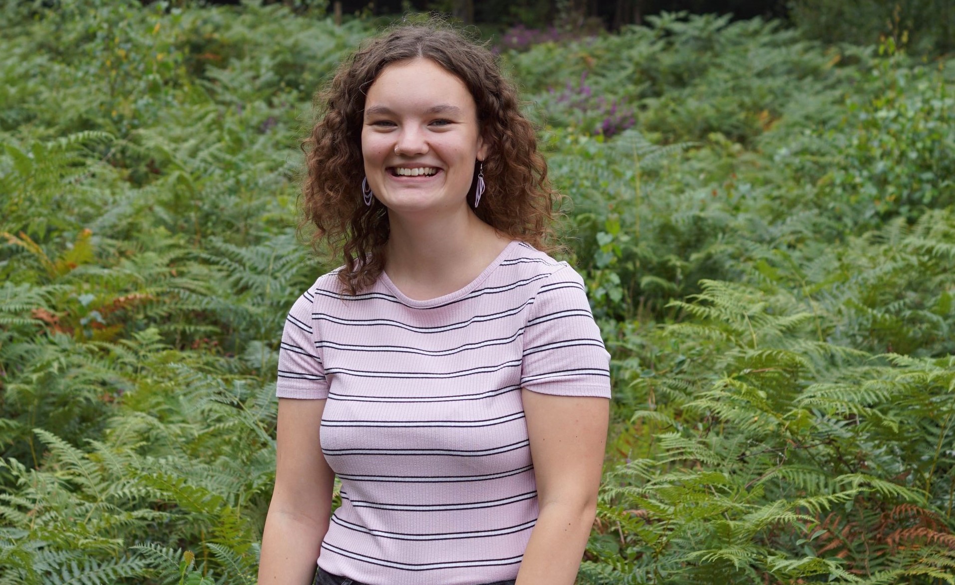 Maisy standing in front of some ferns