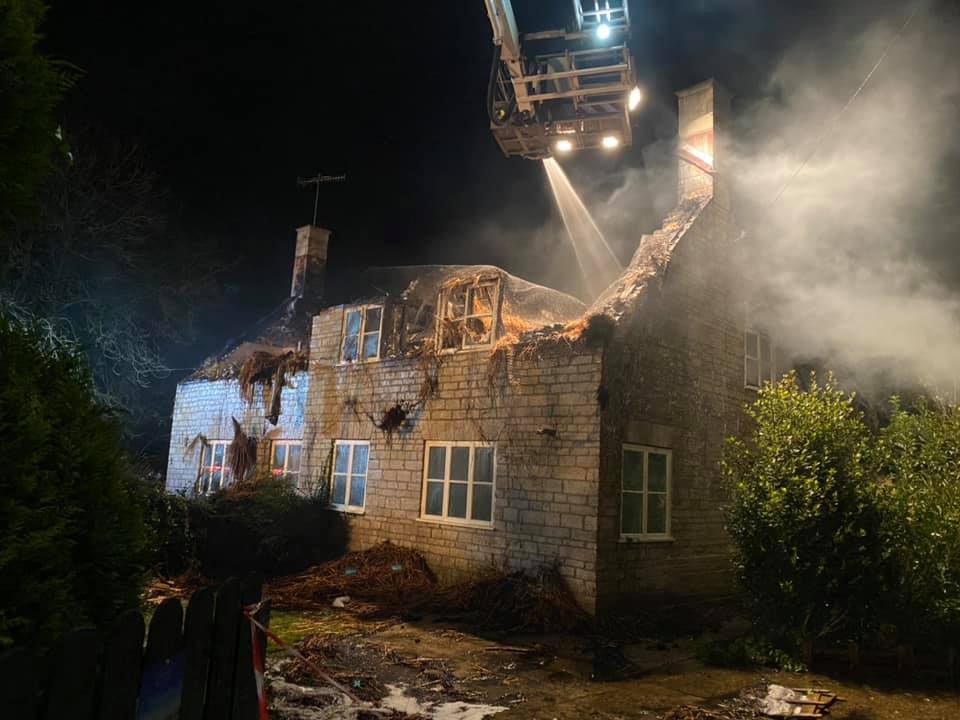 A thatch property fire being extinguished from above, showing the second floor of the building almost entirely destroyed.
