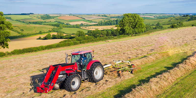 A tractor spinning hay in a field. 