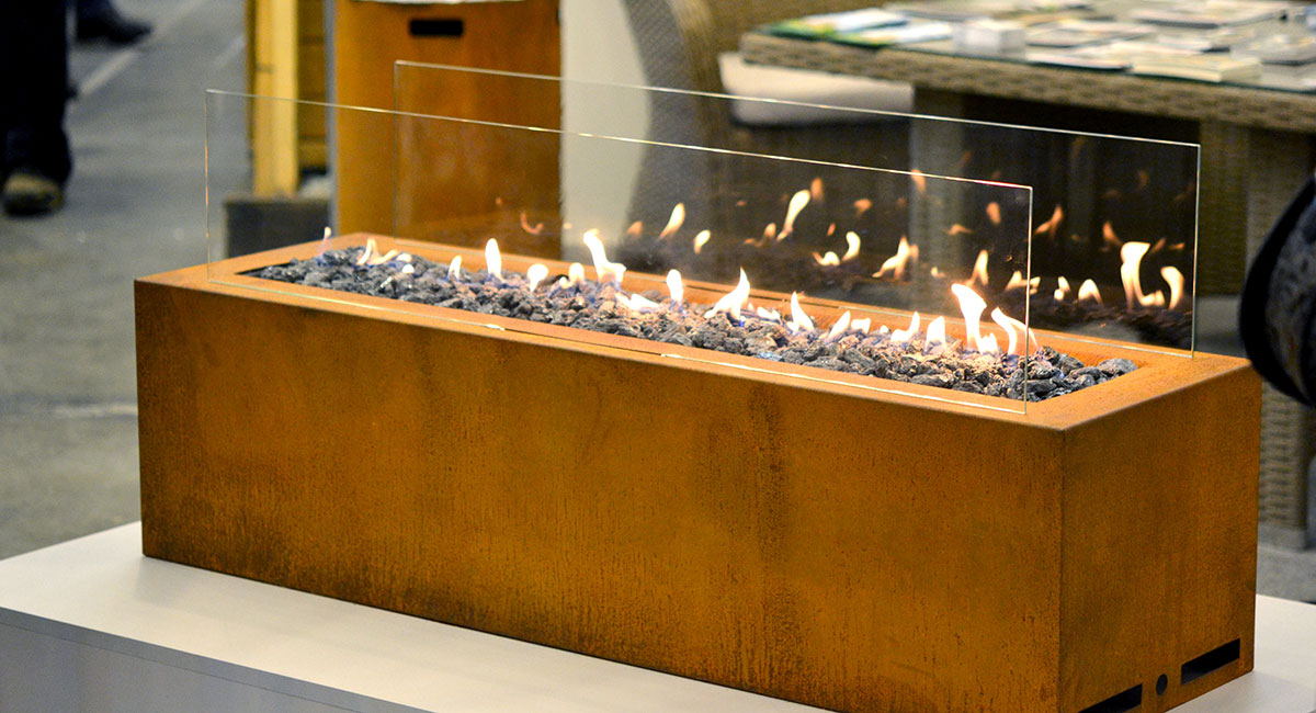 A wooden rectangular bioethanol fire with glass panels around the fire. 