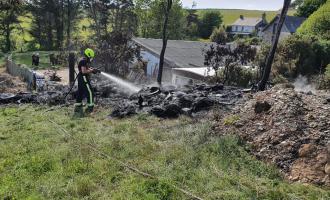 A firefighter extinguishing black, burned grass where an out of control bonfire had spread.