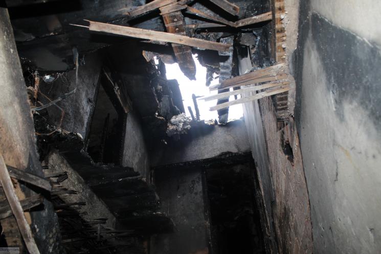 The remains of the staircase to the attic, completely black and burned with no remaining stairway visible.