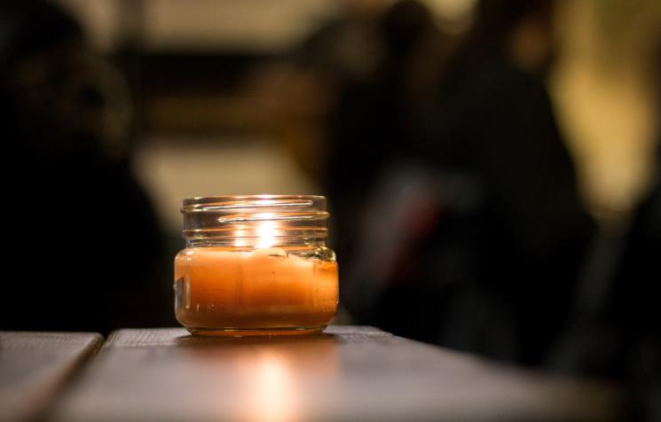 An orange candle in a glass jar glowing.