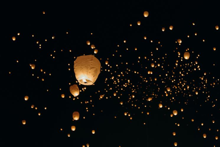 Lots of sky lanterns glowing golden in the dark night sky.