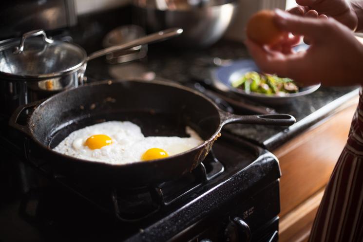 Two eggs cooking in a black frying pan.