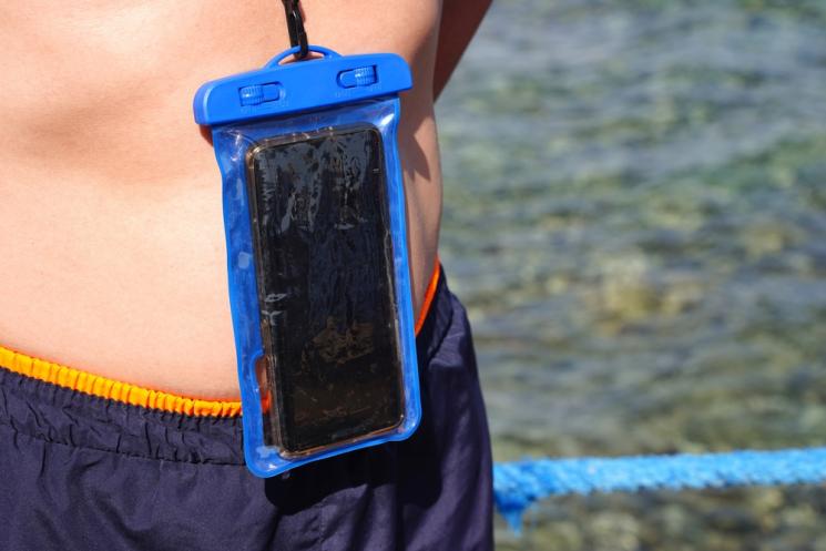 A mobile phone in a waterproof pouch hanging around a man's neck
