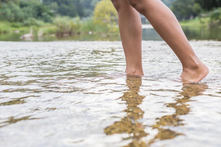 Feet paddling in shallow water in a lake or river