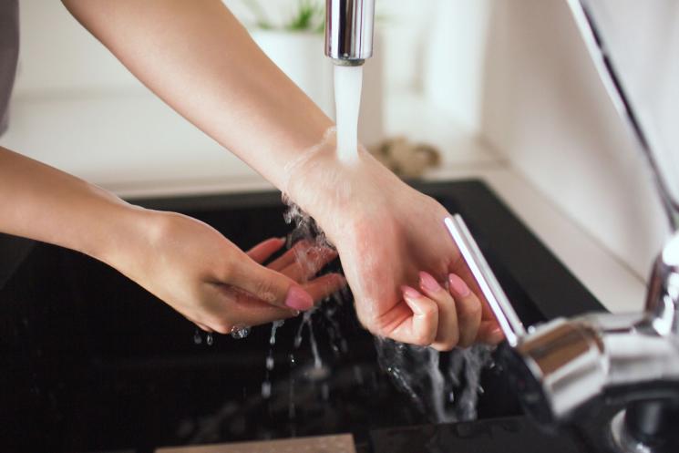 A woman holding her wrists under water coming from a tap