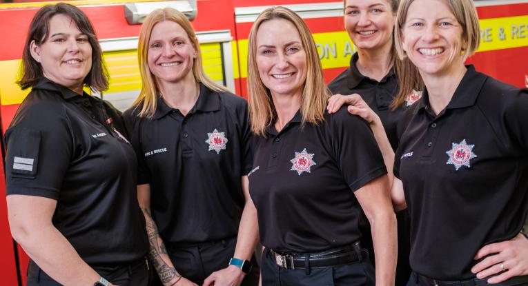 Five female firefighters in front of a fire engine