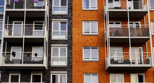 A block of flats with balconies, one side is black and the other is orange.